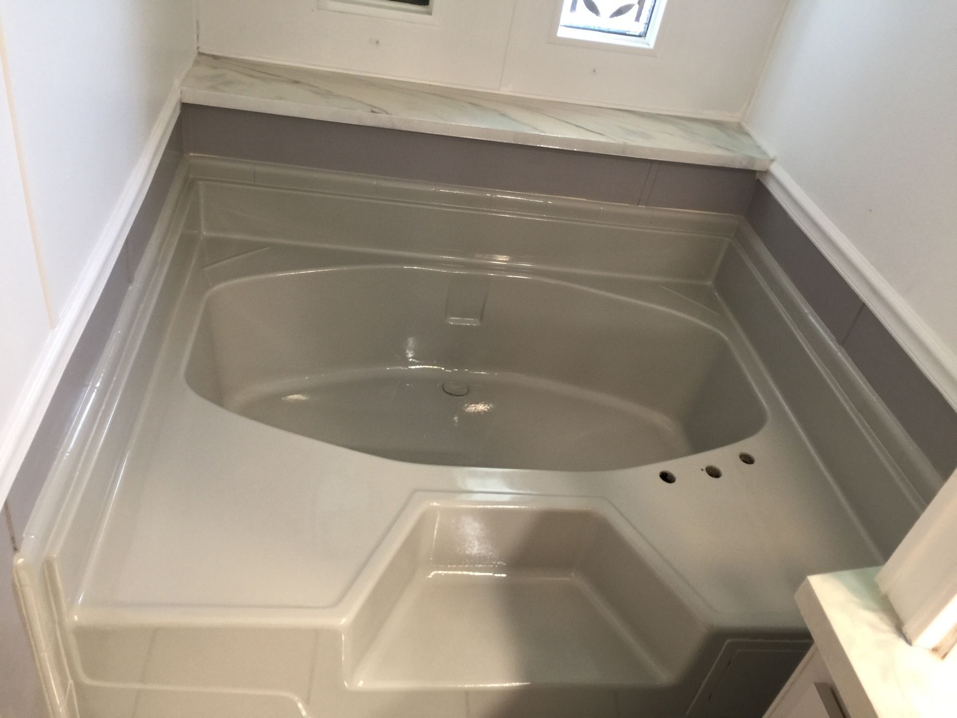 A bathtub in a bathroom with a marble counter top