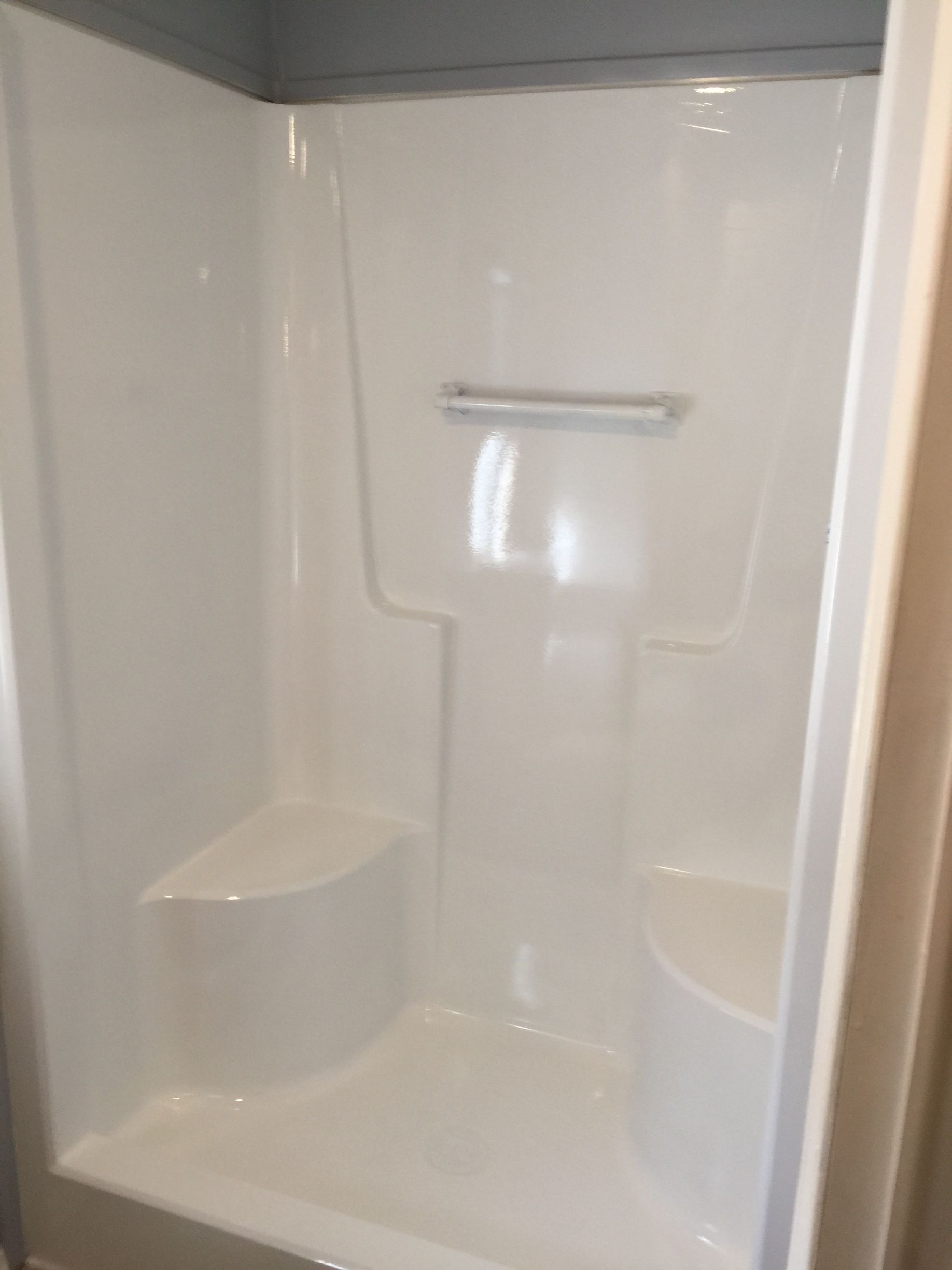 A white shower stall with a seat in a bathroom.