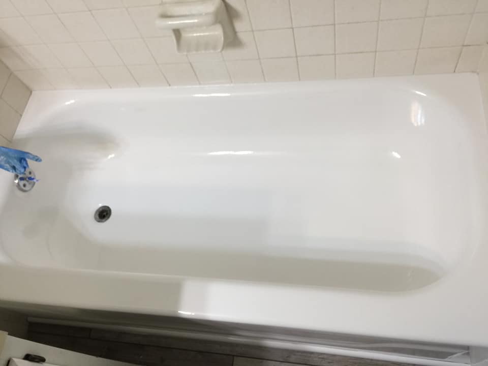 A white bathtub is sitting in a bathroom next to a tiled wall.
