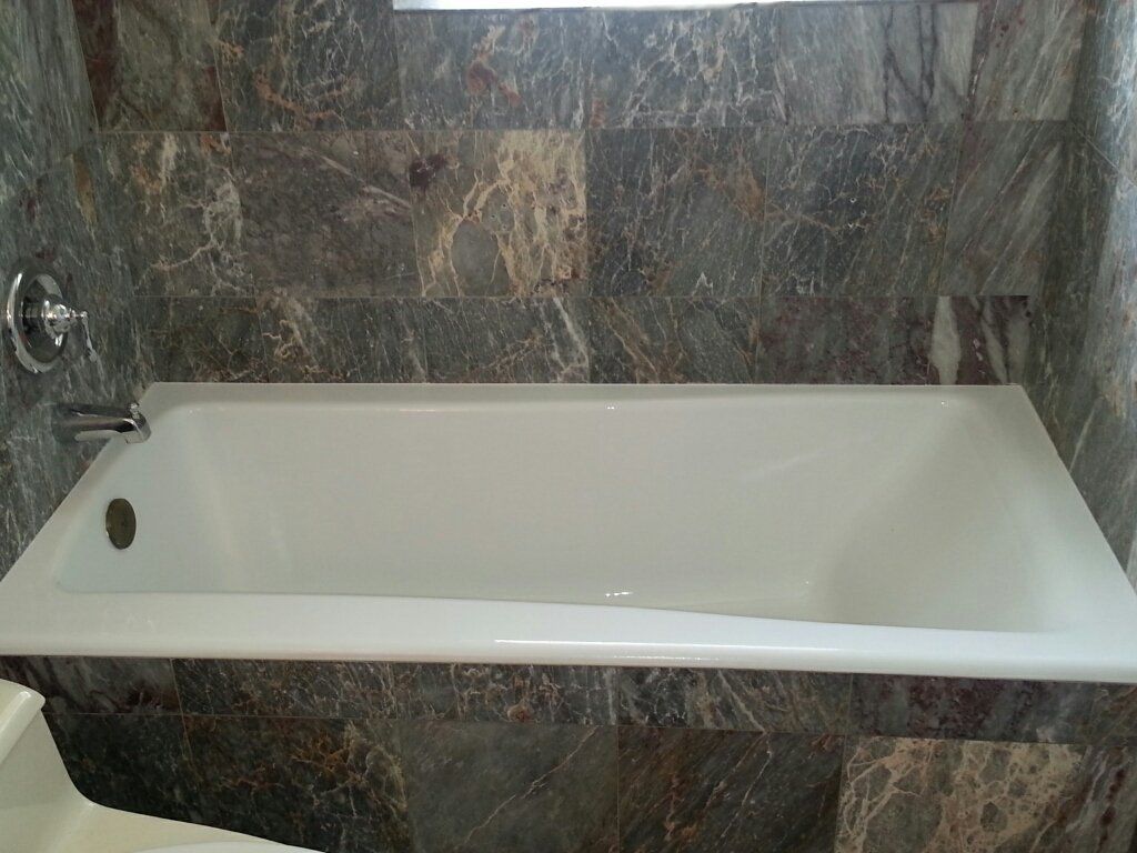 A white bathtub is sitting in a bathroom next to a tiled wall.