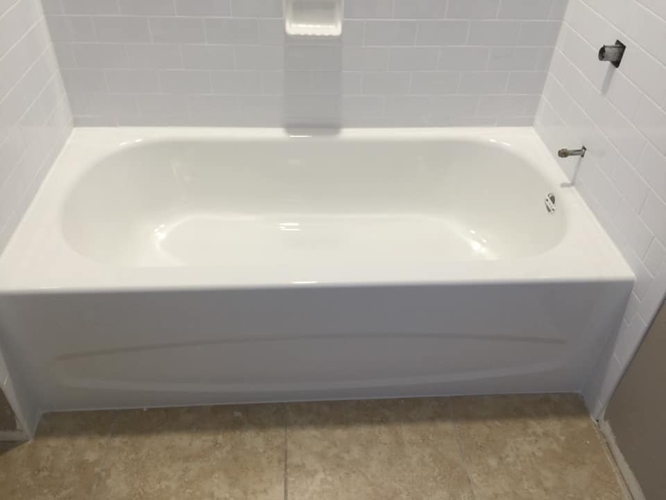 A white bathtub is sitting in a bathroom next to a tiled wall.