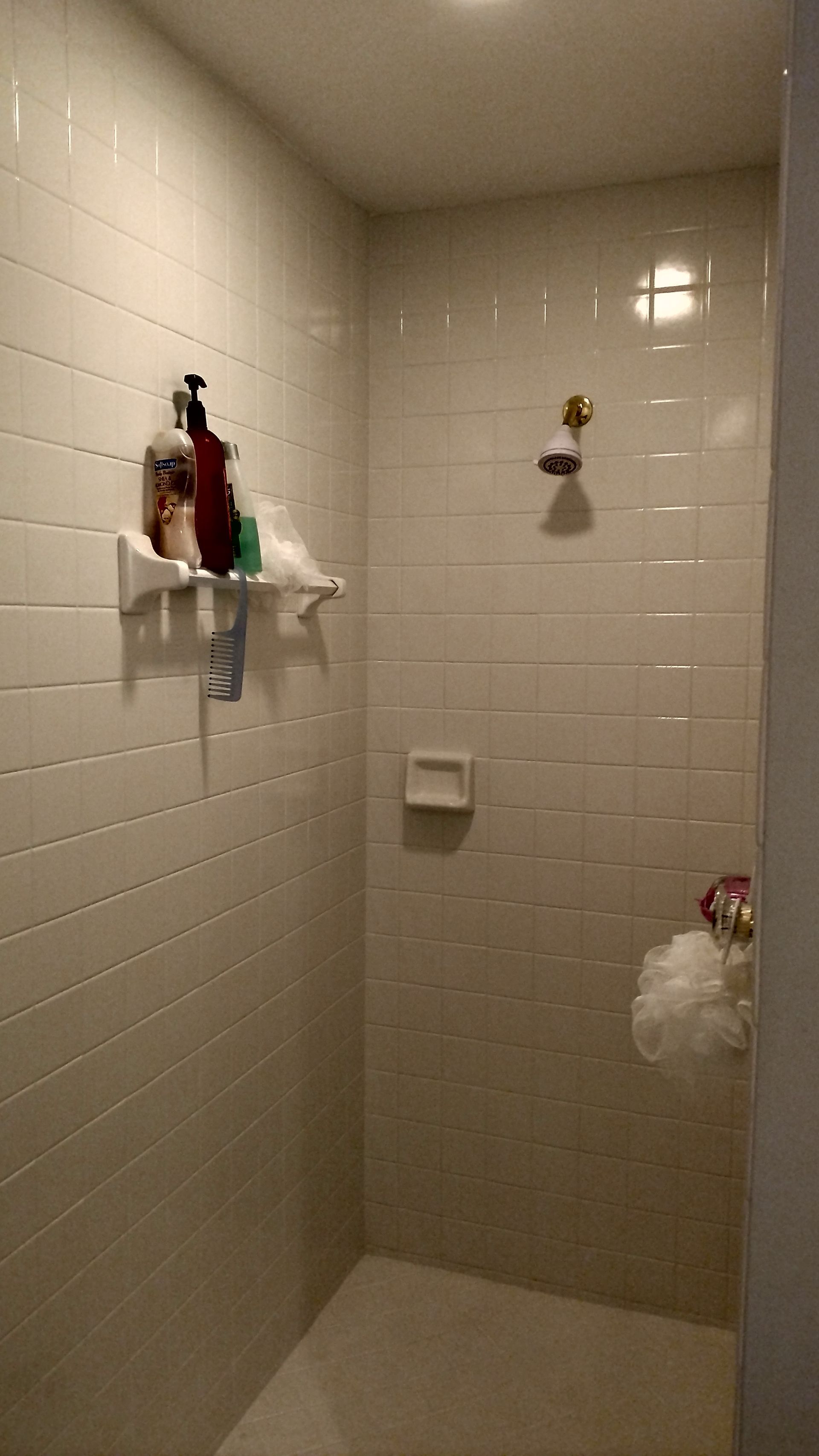 A bathroom with white tile walls and a walk in shower.