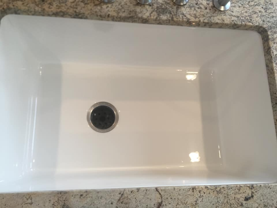 A white sink is sitting on top of a granite counter.