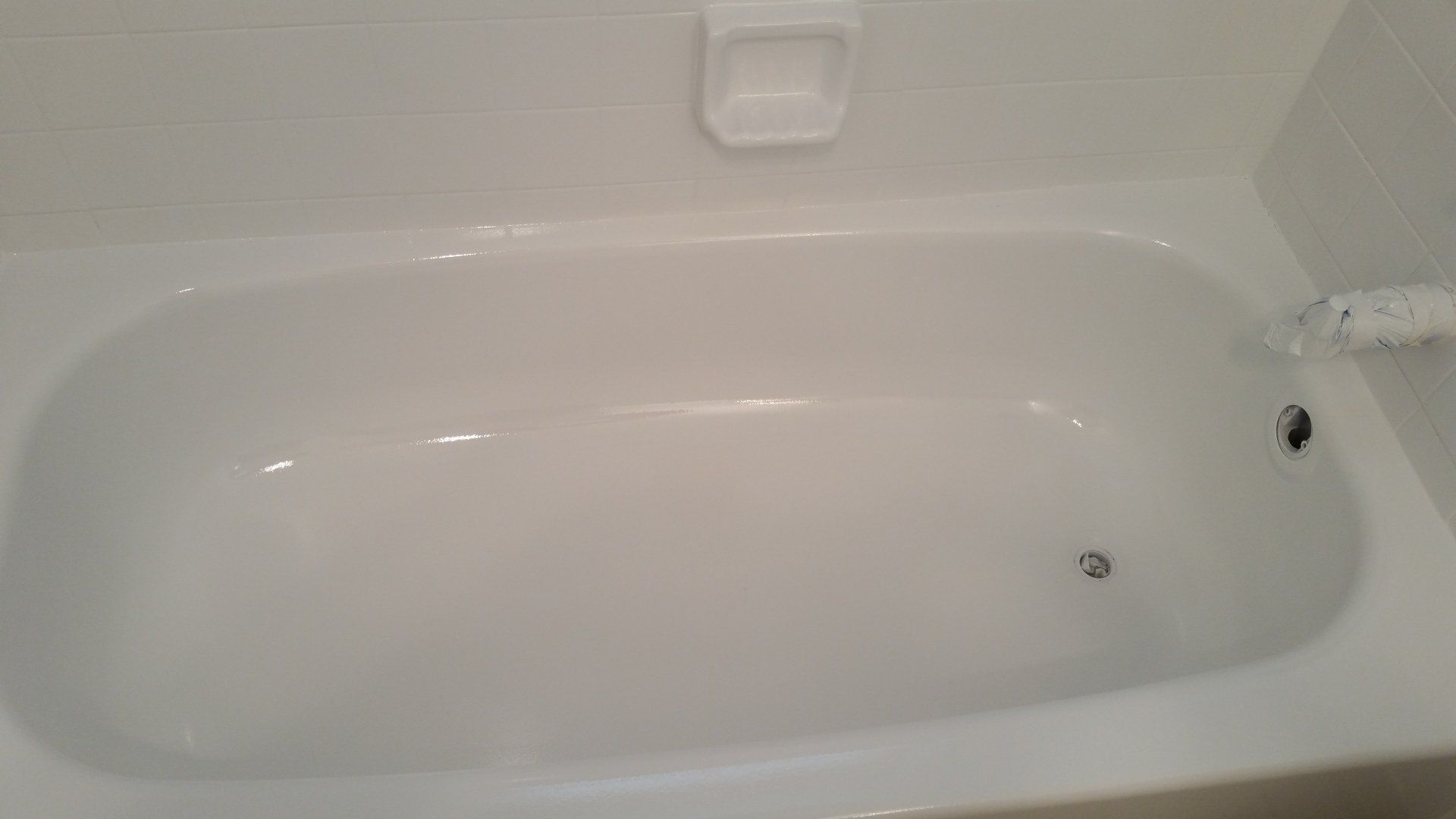 A white bathtub in a bathroom with a soap dish on the wall.