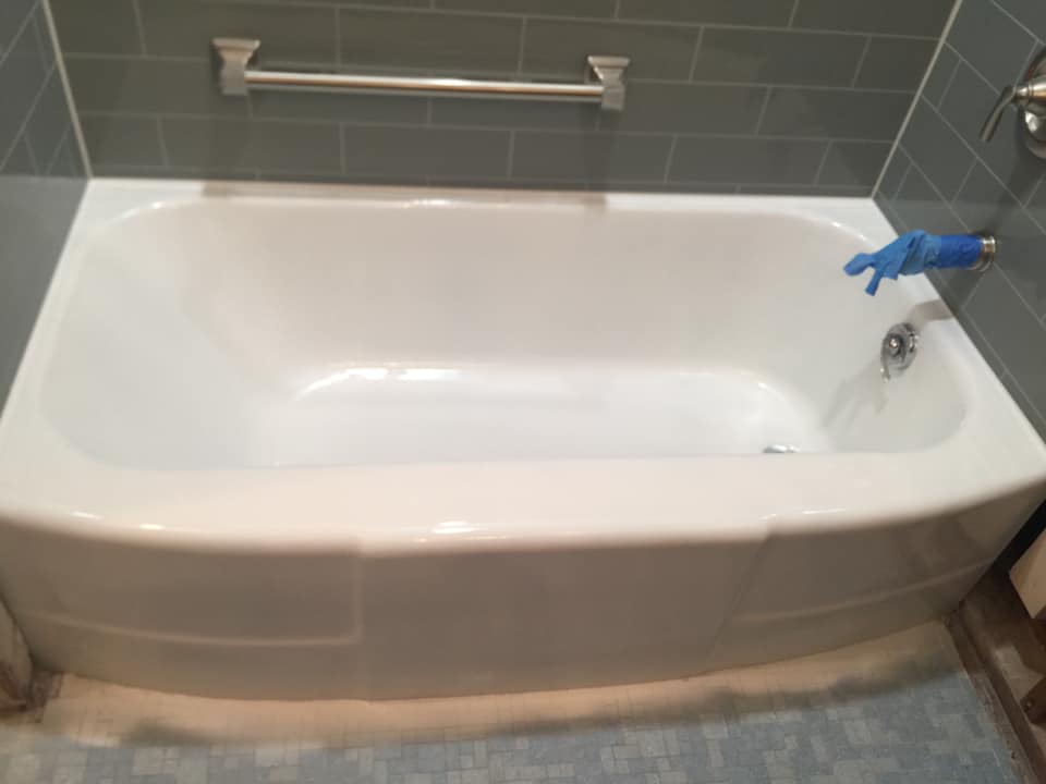 A white bathtub in a bathroom with a blue glove on it.