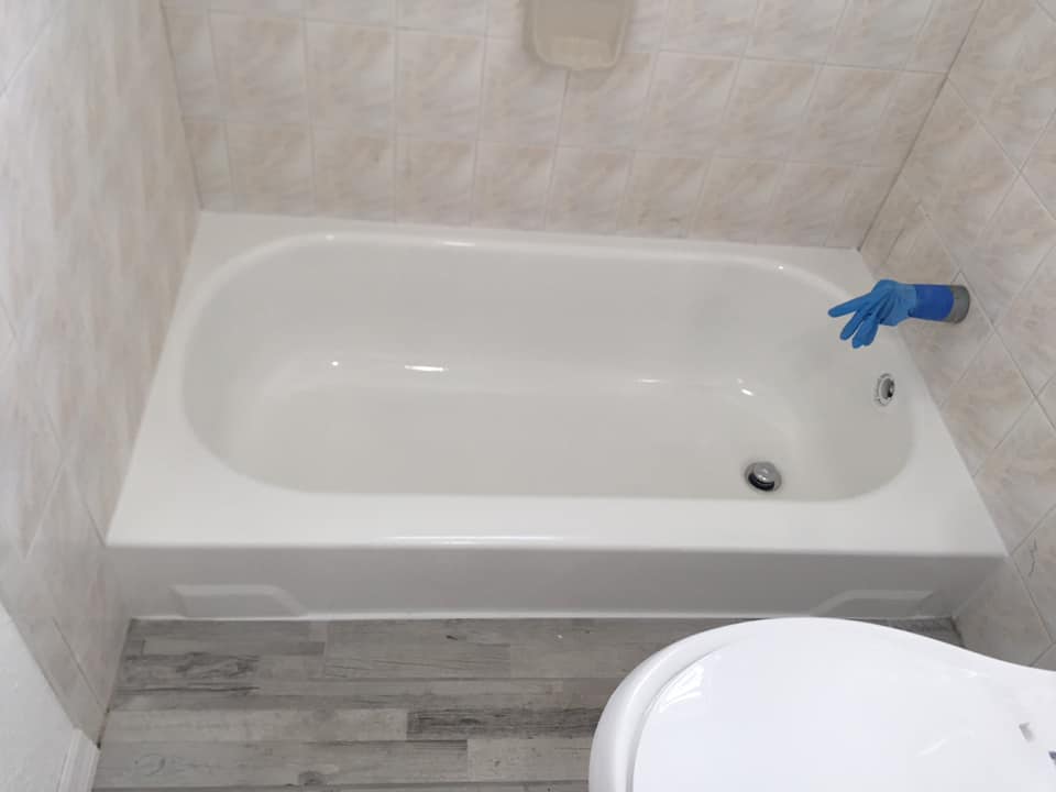 A white bathtub is in a bathroom next to a toilet.