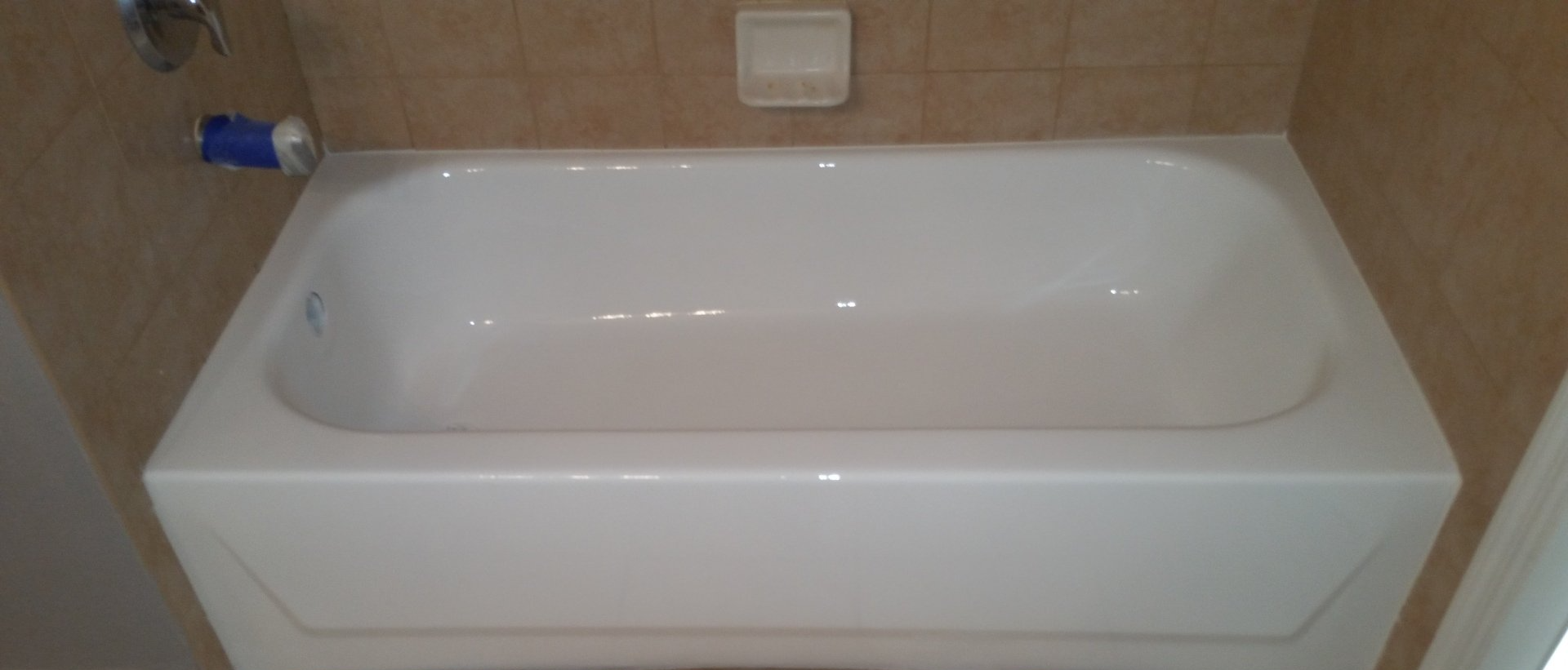A white bathtub is sitting in a bathroom next to a tiled wall.
