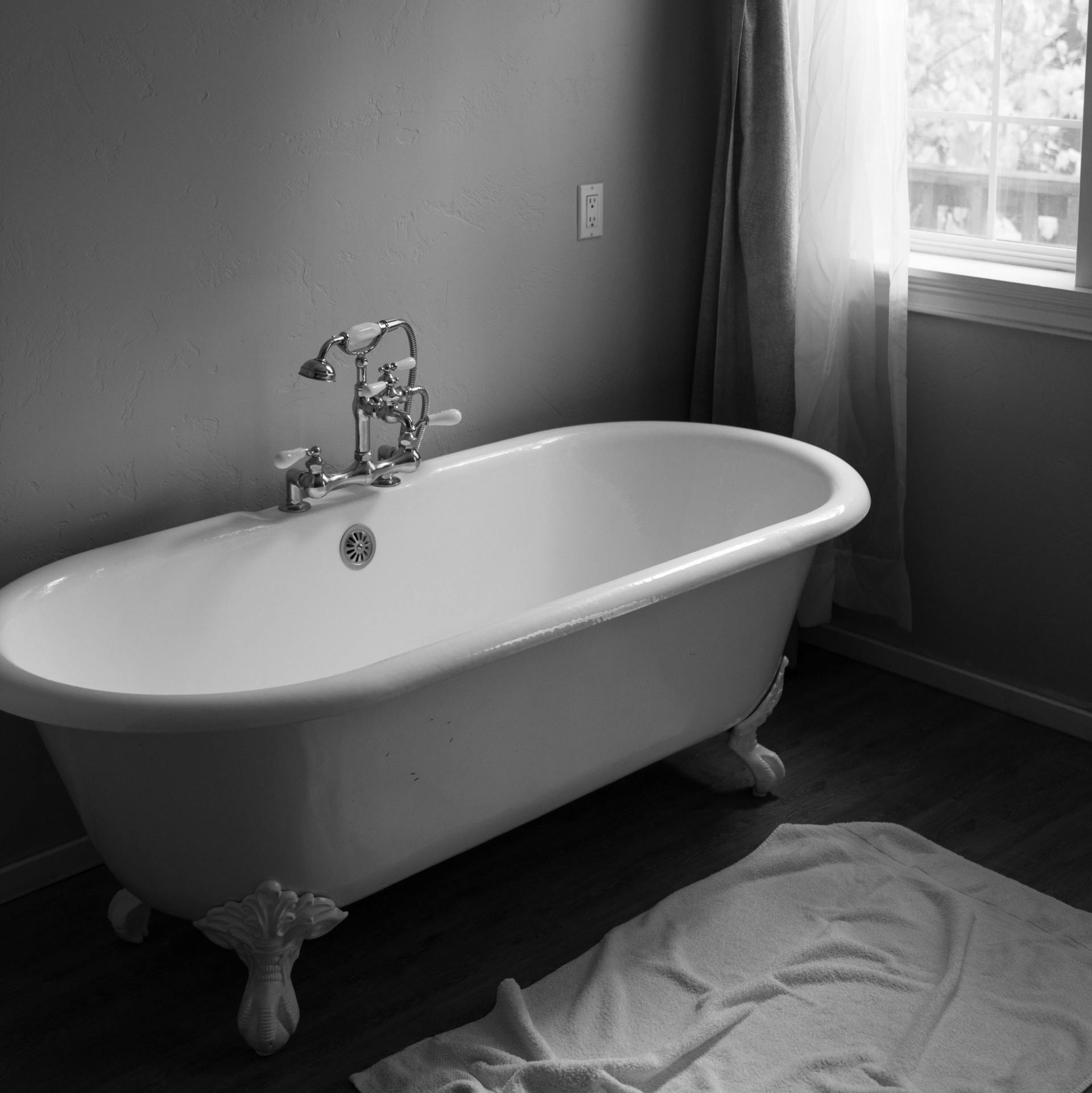A black and white photo of a bathtub in a bathroom