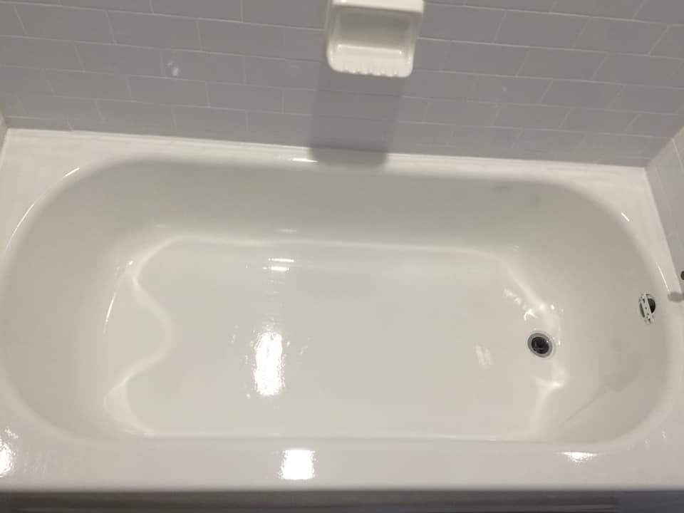 A white bathtub is sitting in a bathroom next to a white tiled wall.