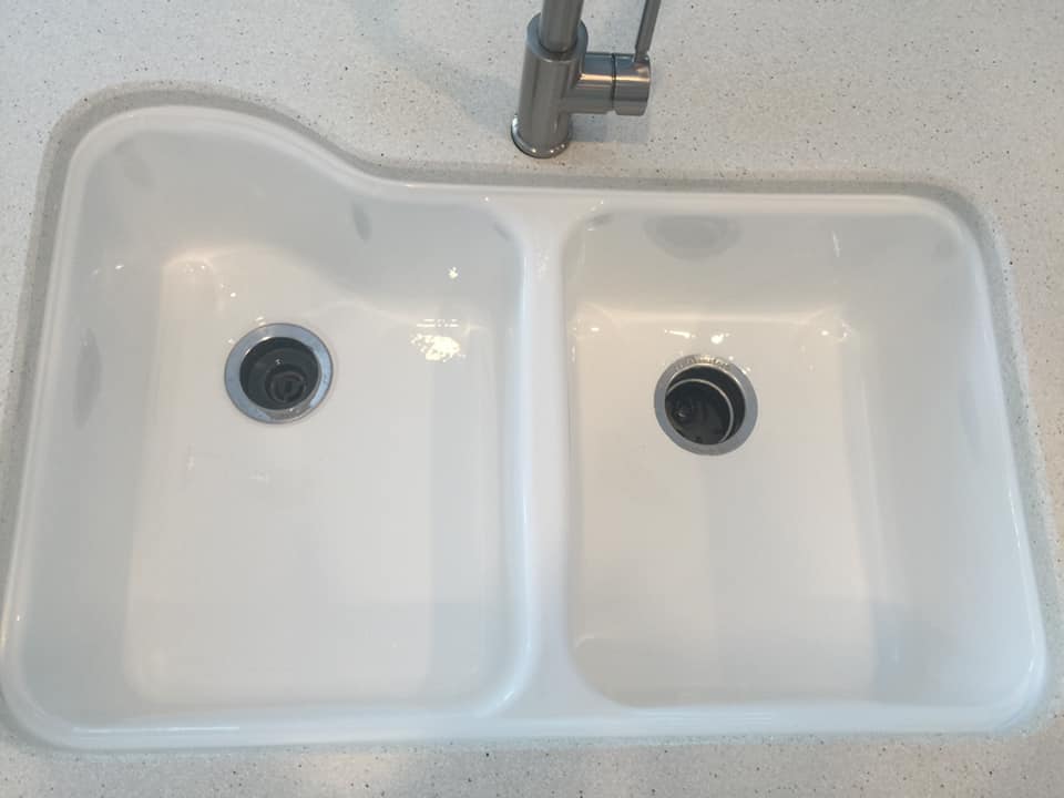 A white kitchen sink with two drains and a faucet.