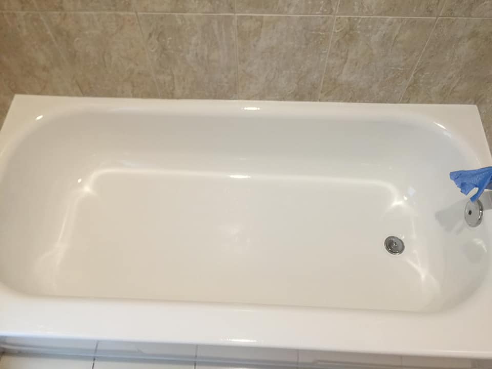 A white bathtub is sitting in a bathroom next to a tiled wall.