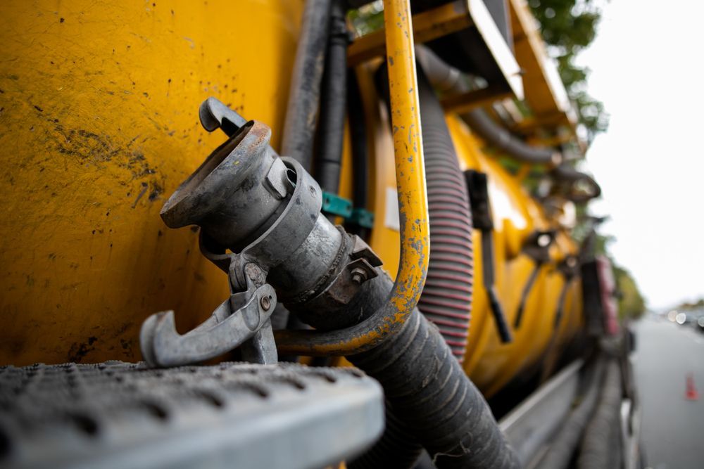 Close-up of yellow road work equipment with metal pipe attachments along a paved road