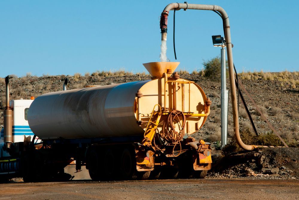 A Water Truck is Being Filled From a Large Overhead Pipe — Tamworth Water Cartage in Gunnedah, NSW