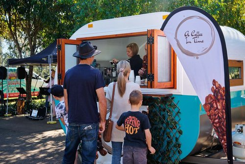 a group of people are standing in front of a food truck .