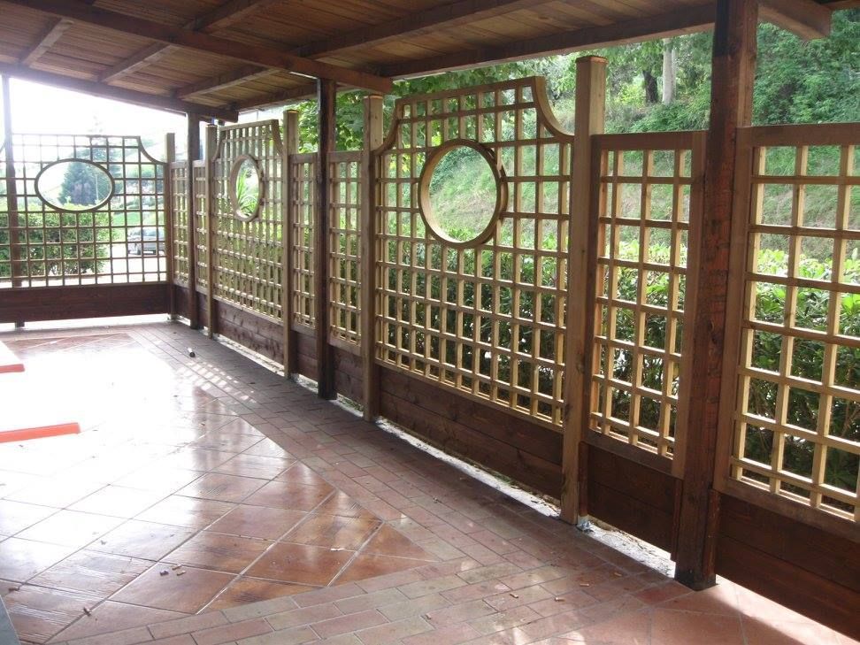 Un balcone in pietra con ringhiera bianca si estende lungo un edificio bianco caratterizzato da porte scorrevoli in vetro con telaio in legno.
