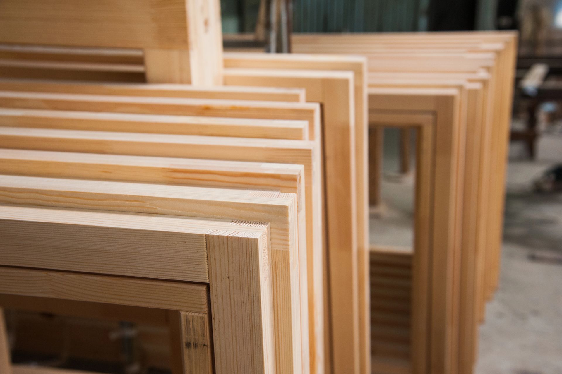 Pila di telai di finestre o porte in legno riposti in un'officina.
