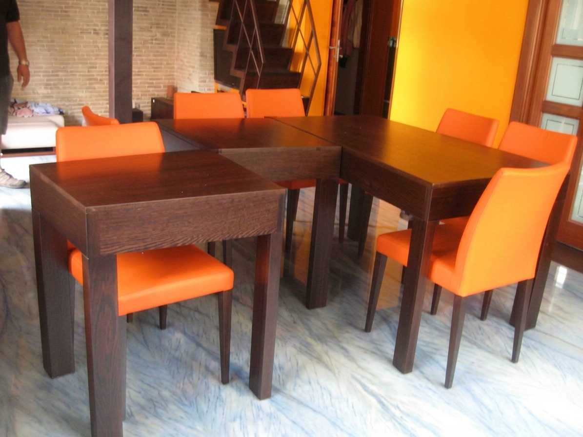 Un set da pranzo modulare con tavoli in legno scuro e sedie imbottite color arancione acceso in una stanza con pavimento effetto marmo.