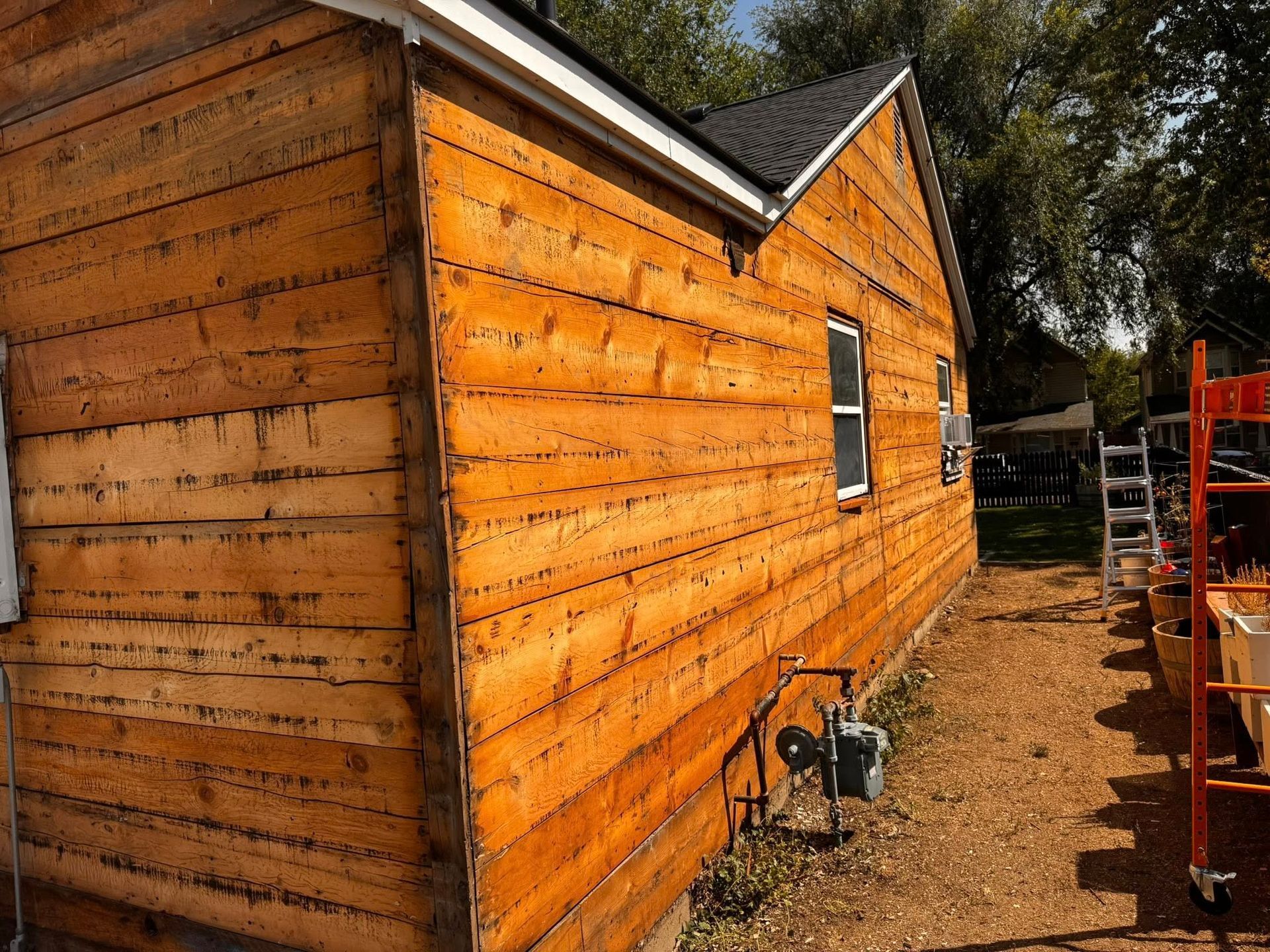 Wooden-sided house, exterior view. Orange-toned wood, white trim, small windows.