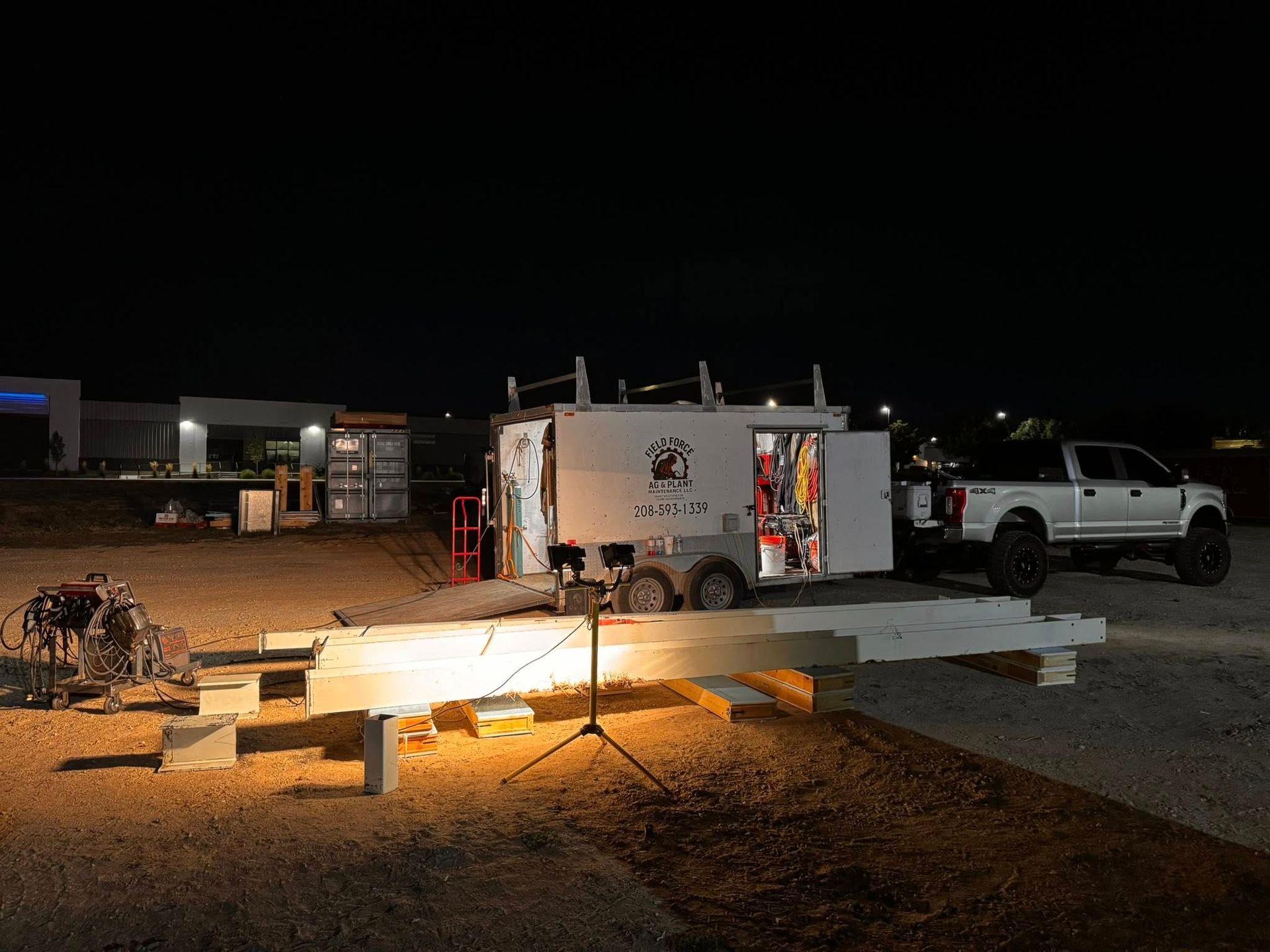 Night shot of trailer with open door and truck, set up with equipment and lights outdoors.