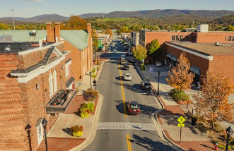 Downtown street with parked cars, brick buildings, autumn trees, and mountains in the background Downtown street with parked cars, brick buildings, autumn trees, and mountains in the background