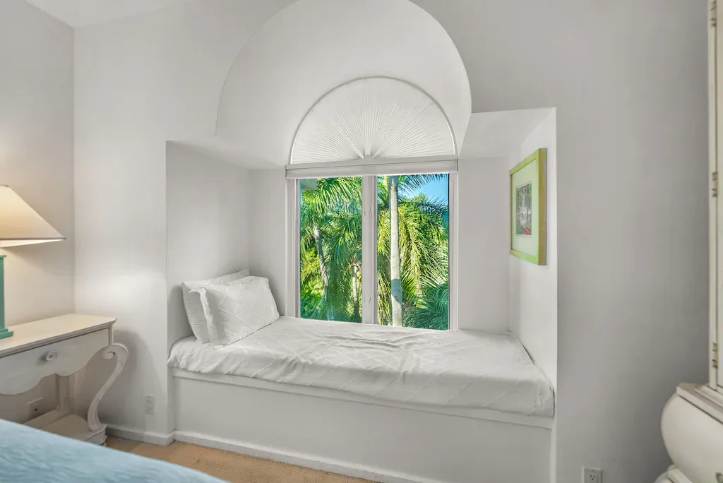 Bedroom alcove with built-in white bed, window, and decorative white, arched top.