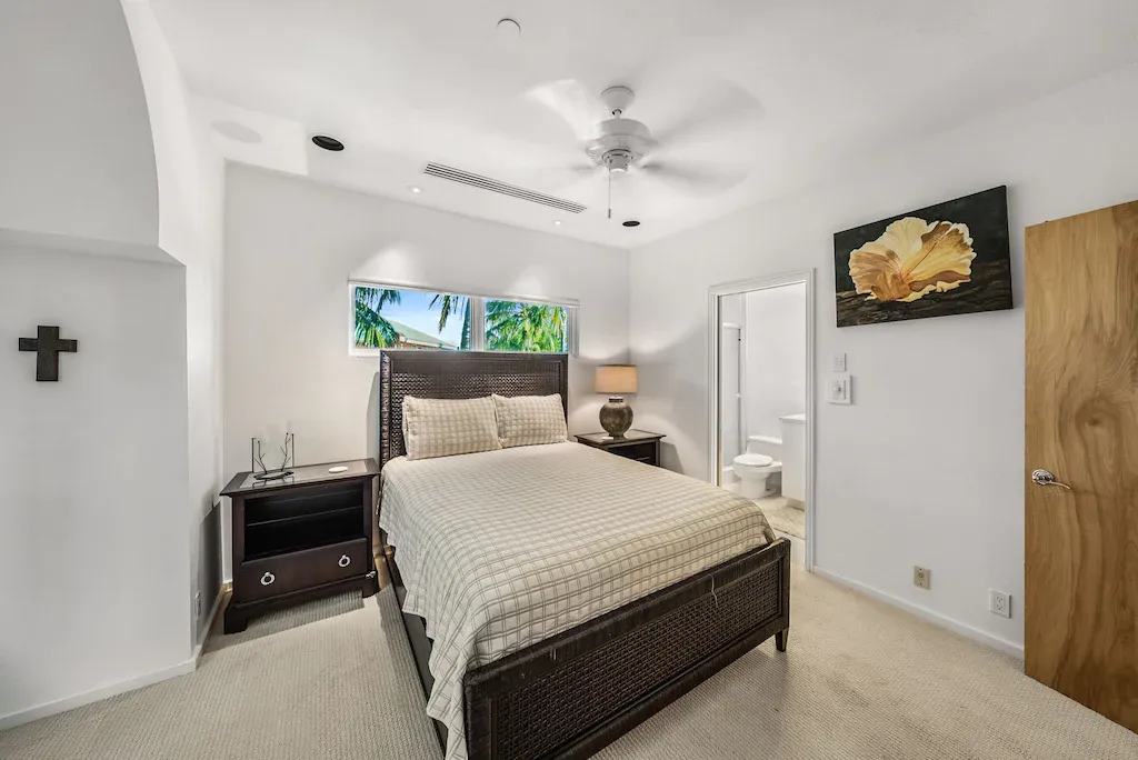 Bedroom with a bed, nightstand, artwork, and a cross on the wall.