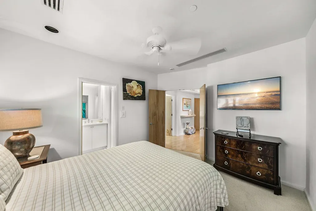 Bedroom with bed, nightstand, dresser, and an open doorway to a bathroom.