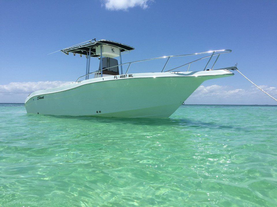 White boat floats in clear turquoise water under a blue sky.