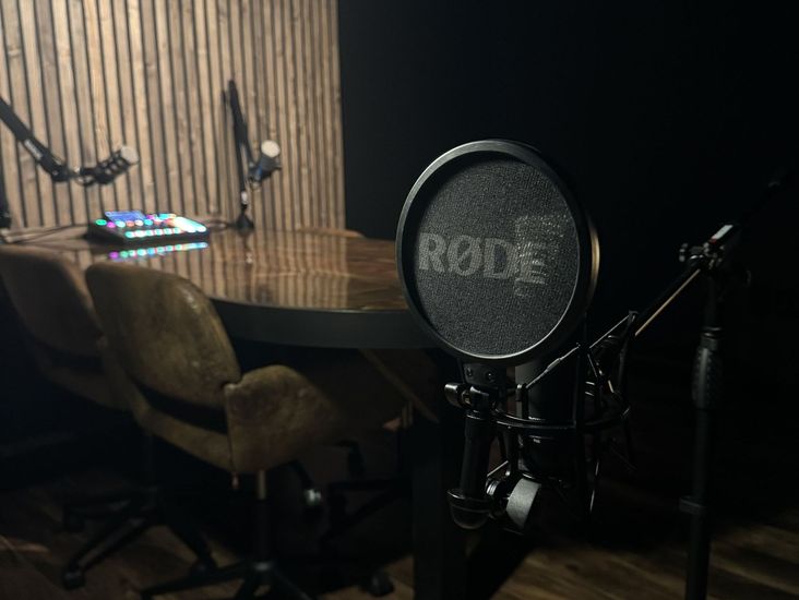 A rode microphone is sitting in front of a table in a dark room.