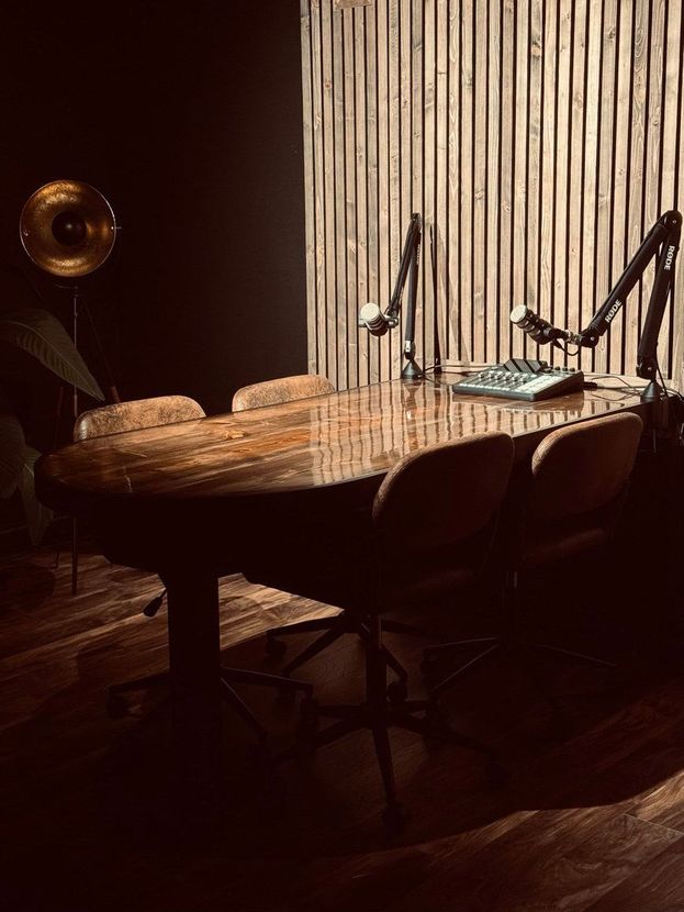 A wooden table with two microphones on it in a dark room.
