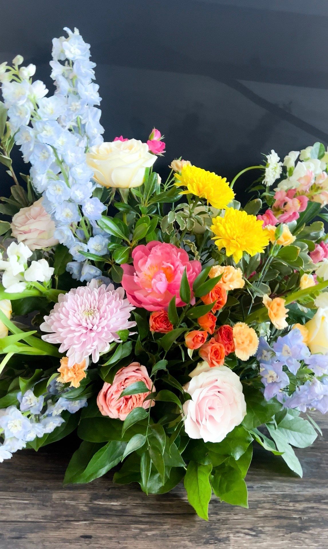 A bunch of flowers are sitting on top of a wooden table.