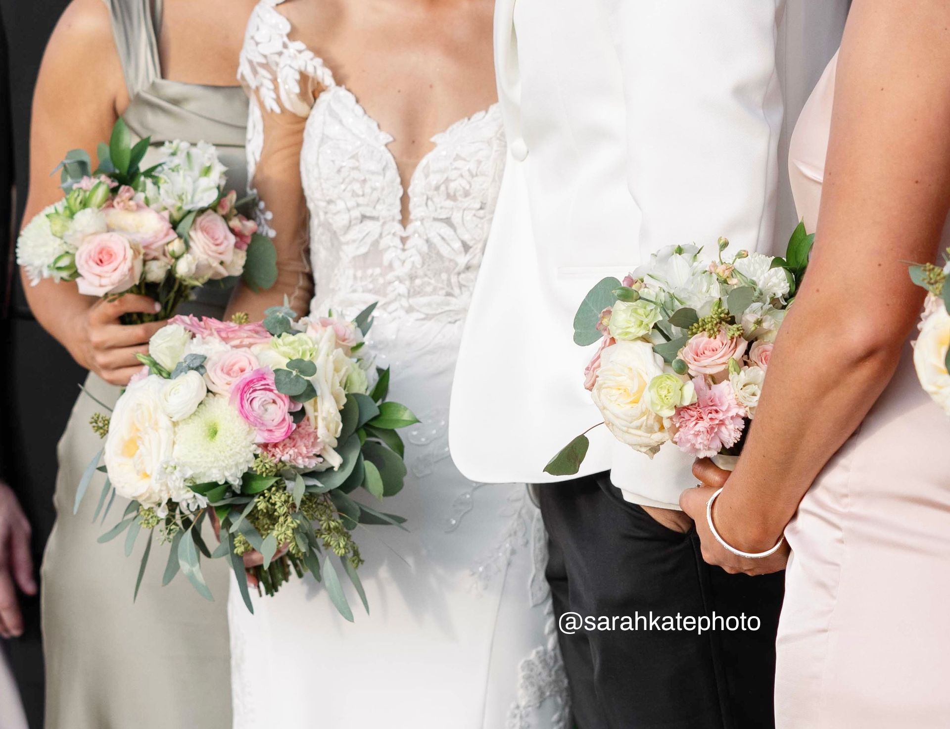 A bride and groom are standing next to each other holding bouquets of flowers.