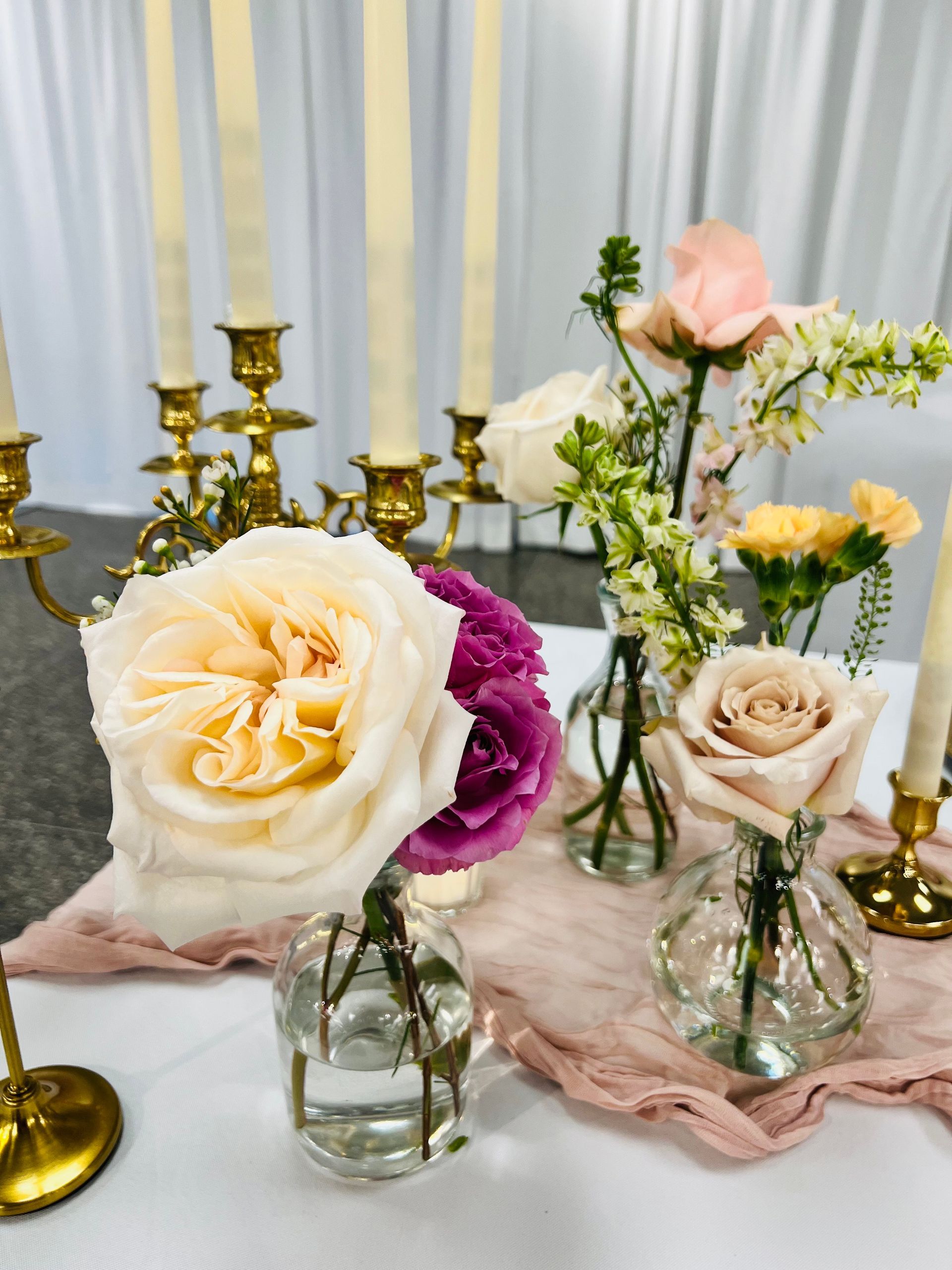 A table with vases of flowers and candles on it