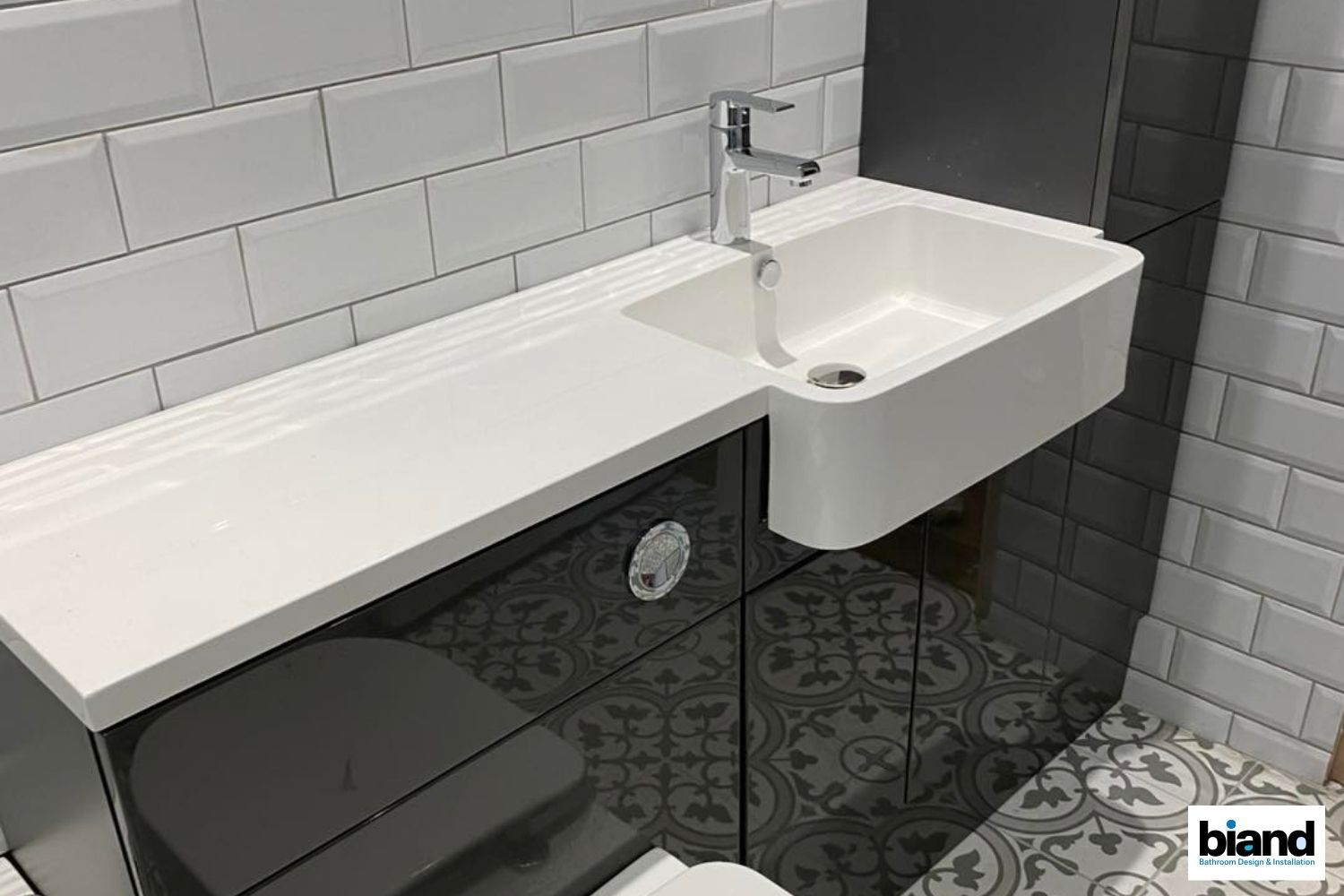 Modern bathroom with white sink and faucet on a dark gray cabinet. White subway tiles on the wall.