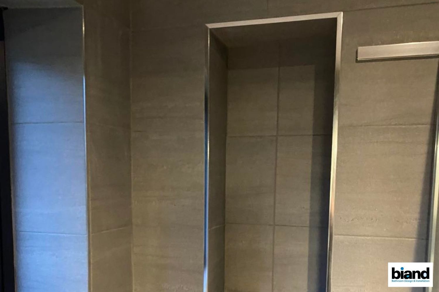Recessed wall niches with silver trim in a tiled shower.