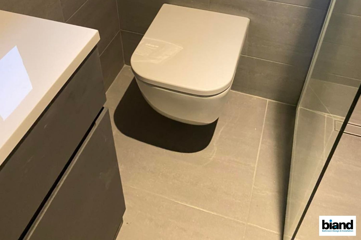 Modern bathroom with a wall-mounted toilet and grey tile floors.