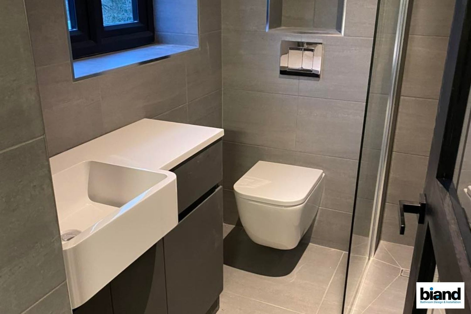 Modern gray bathroom with floating toilet, sink, and storage cabinet.