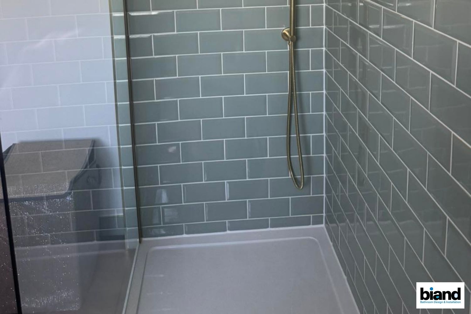 Gray tiled shower with glass enclosure and built-in seat.