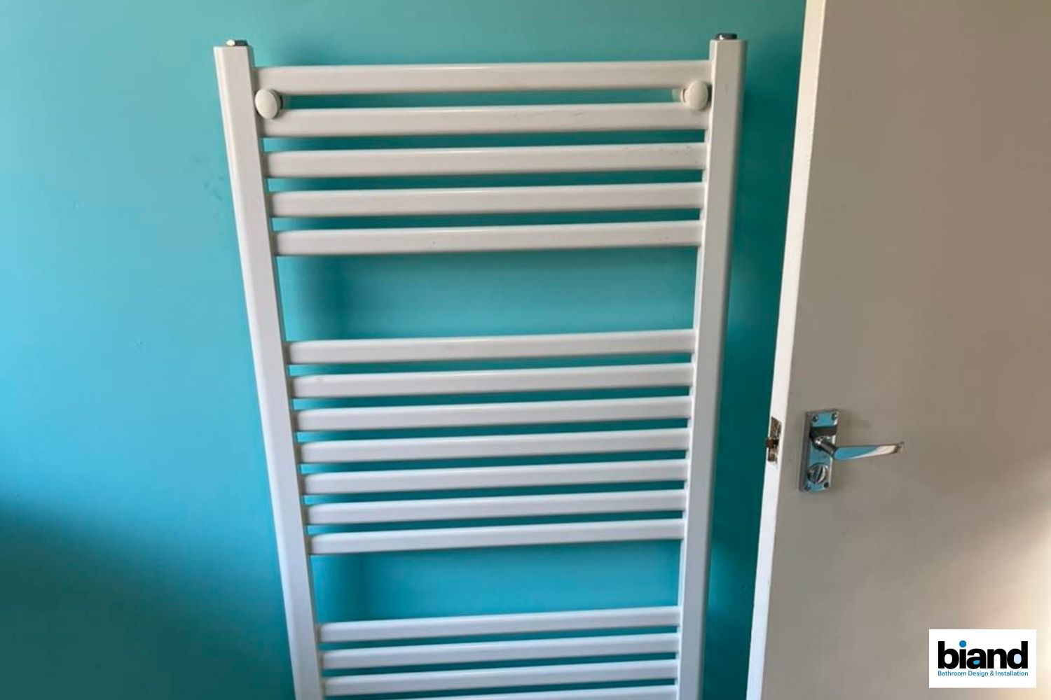 White towel radiator on a blue wall next to a white door.