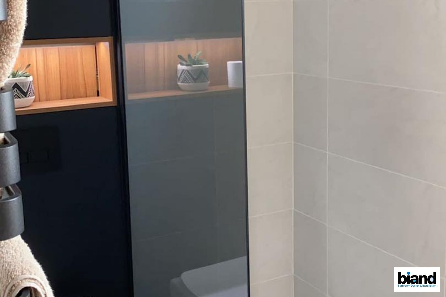 Bathroom with mirror, tiled walls, and built-in wooden shelf displaying plants and a candle.
