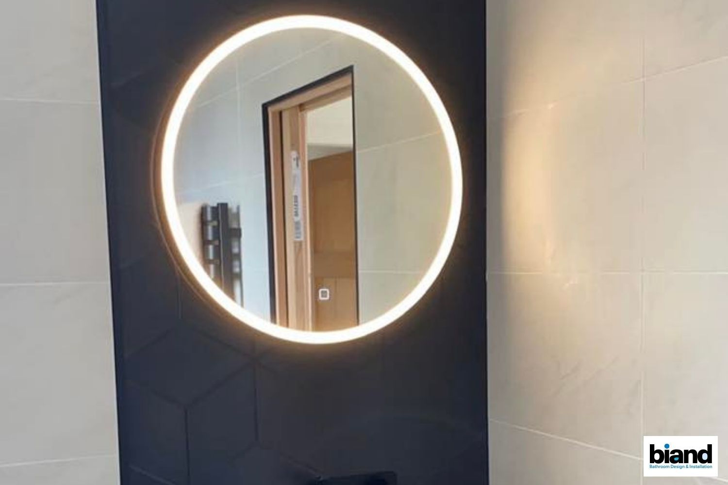 Round illuminated bathroom mirror mounted on dark blue wall.