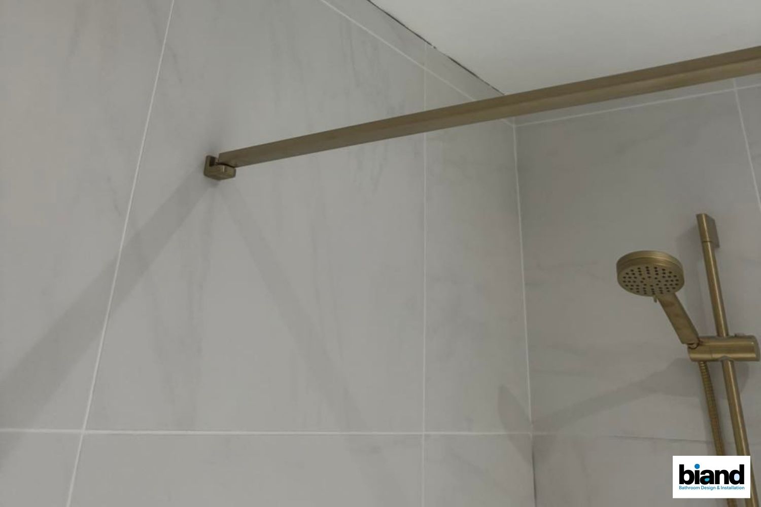 Shower with brass fixtures on gray tile walls.