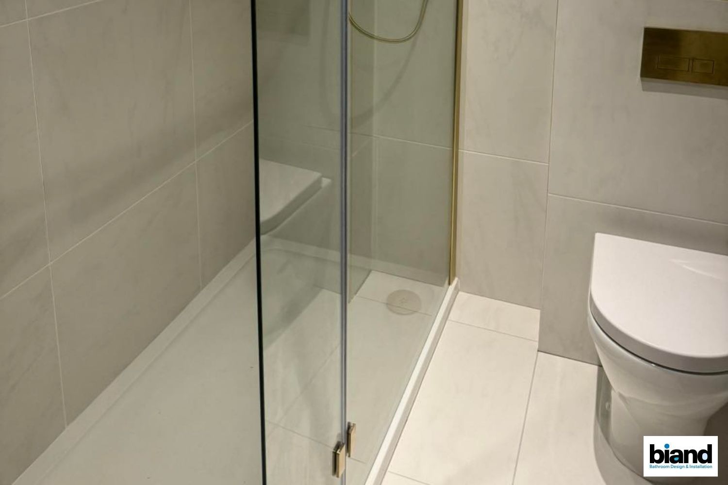 Bathroom with white tiles, a clear glass shower door, and a white toilet.
