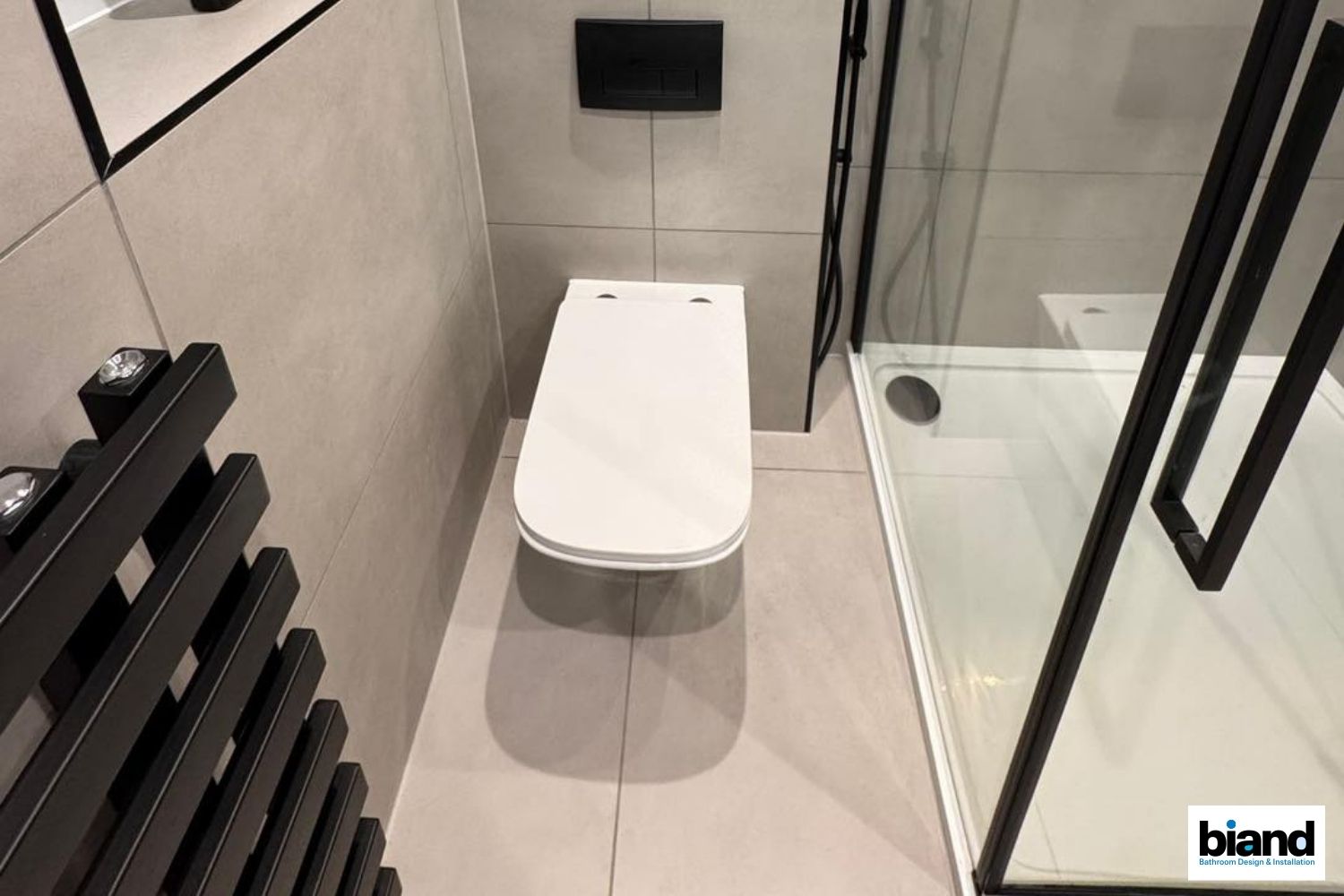 Modern bathroom with a white toilet, shower, and dark accents.