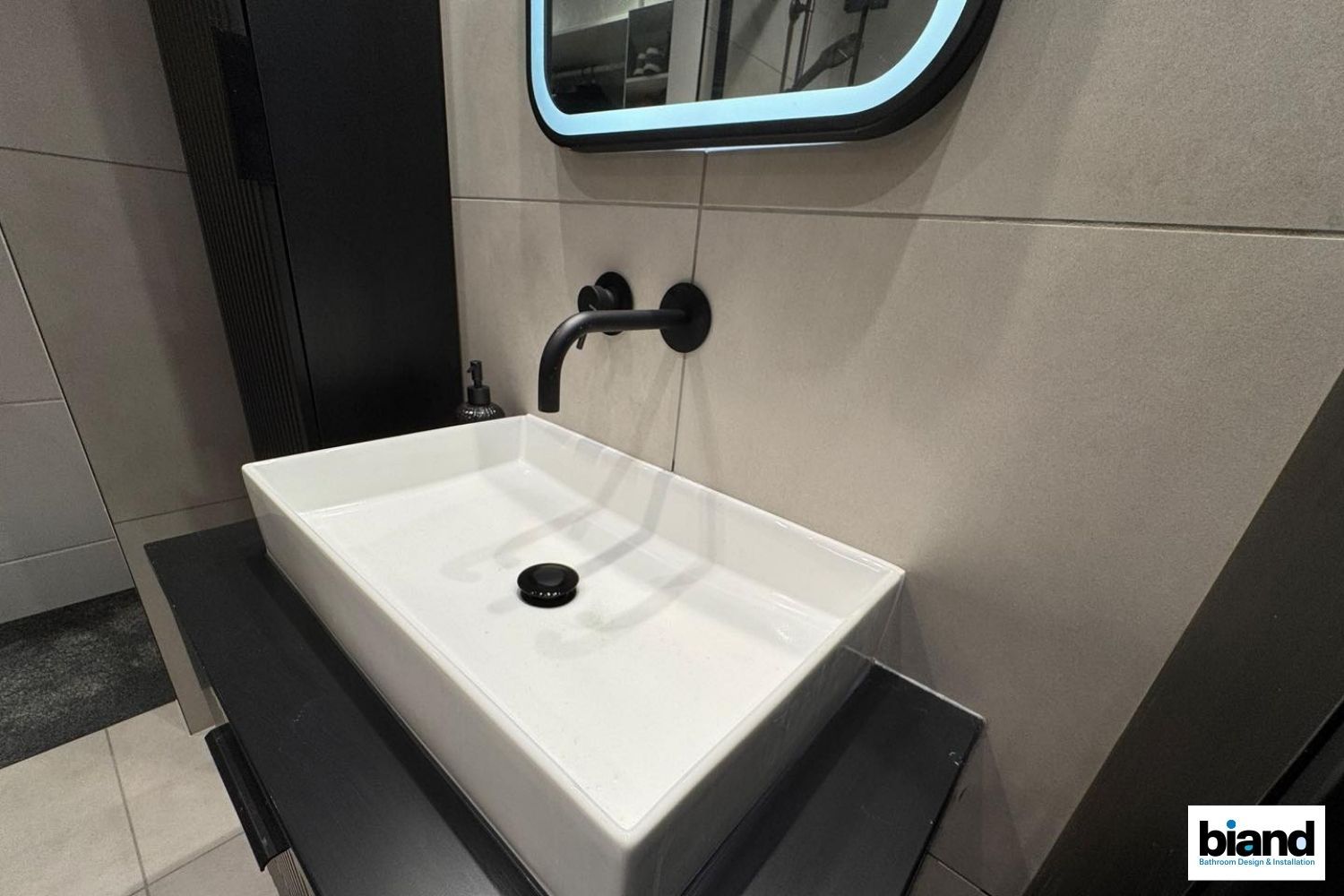 Modern bathroom with rectangular sink, black faucet, mirror, and dark cabinetry.