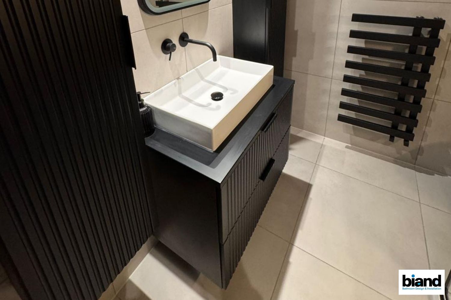 Modern black bathroom vanity with a white rectangular sink.