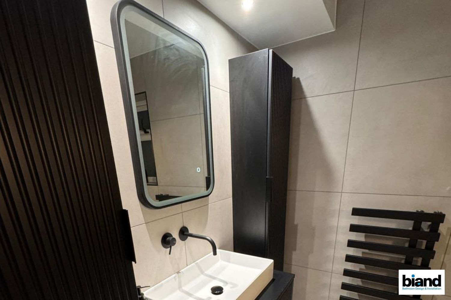 Modern bathroom: black cabinet, mirror, and sink; black wall-mounted faucet; heated towel rack.