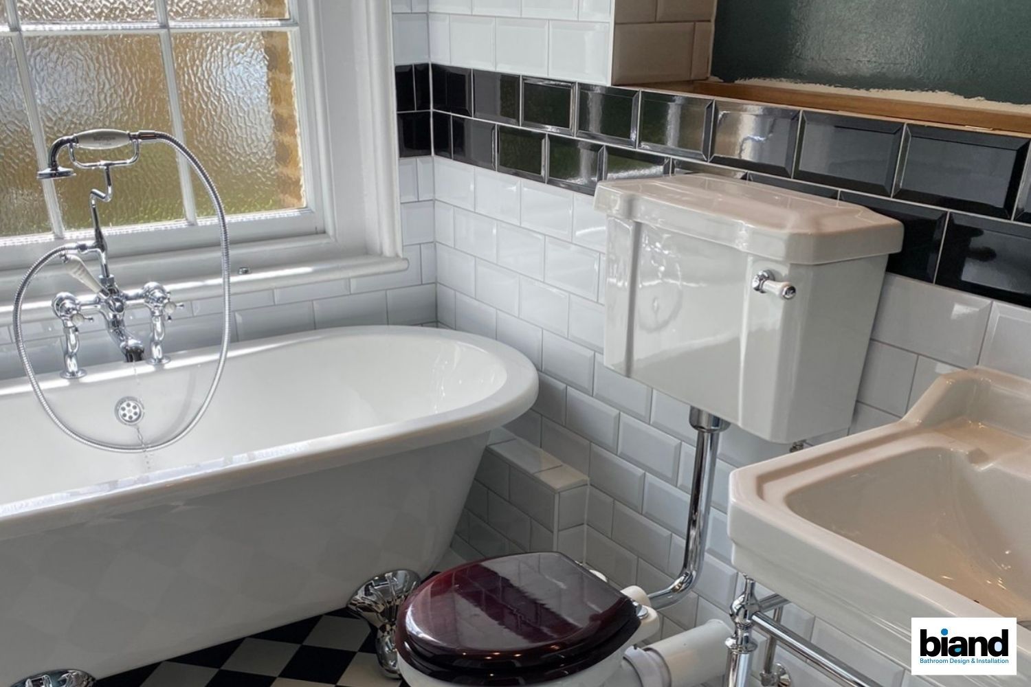 Bathroom with a white bathtub, toilet, and sink; black and white tile floor.