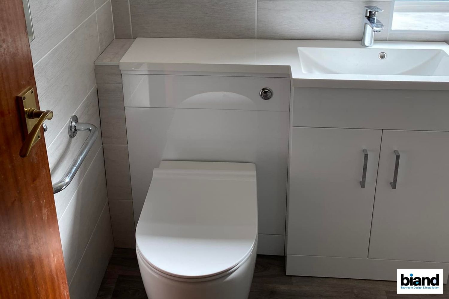 White toilet and sink in a small bathroom with gray tile walls.