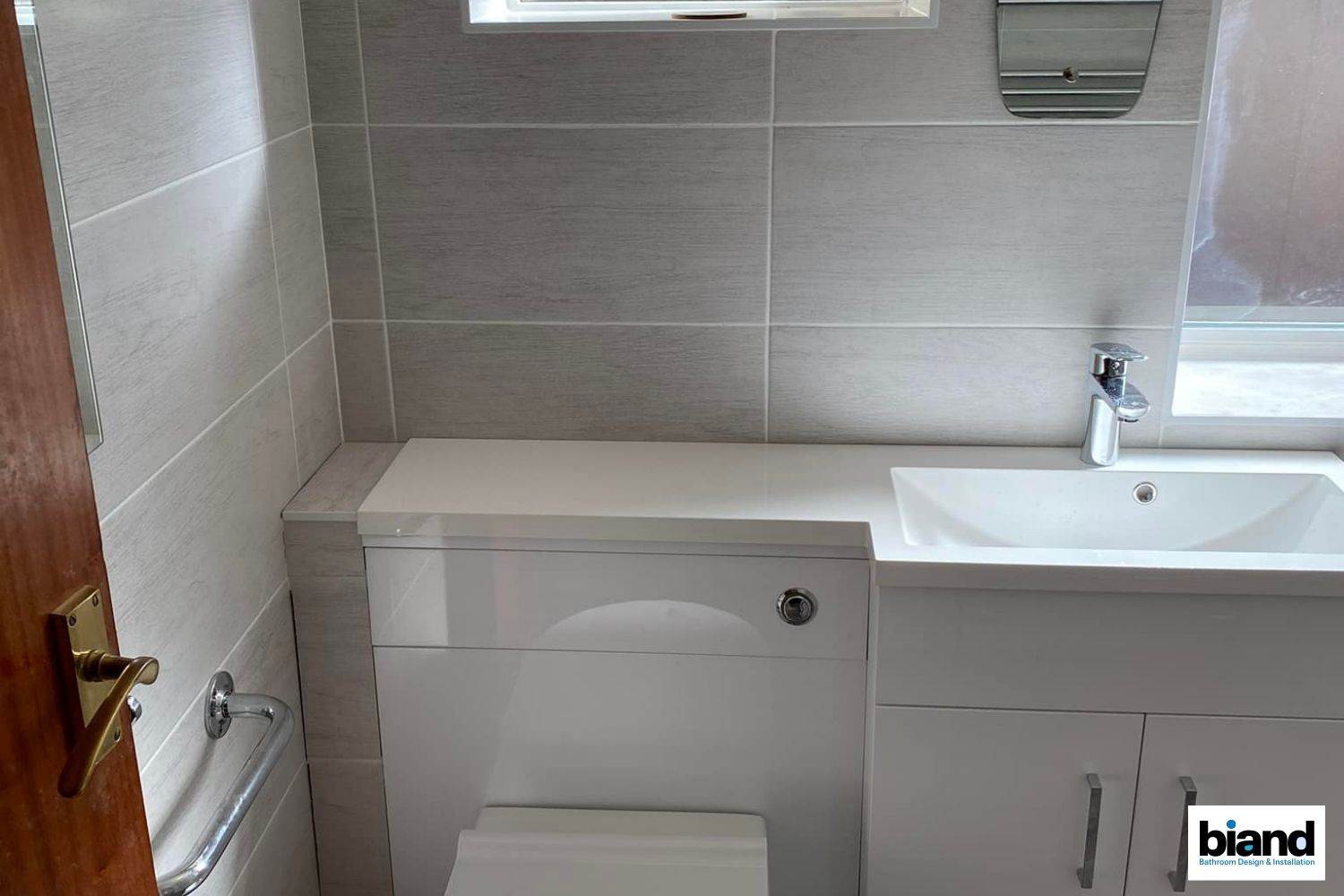 Small bathroom with gray tiles, white toilet, sink, and vanity.